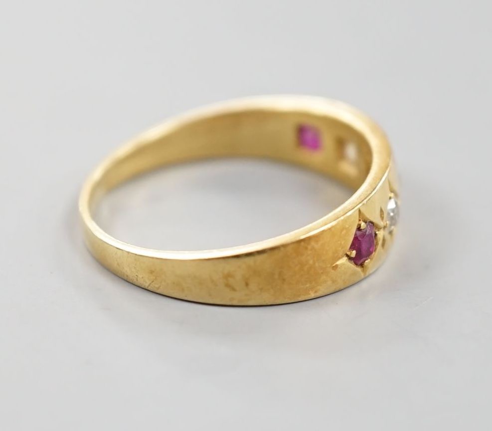 An early 20th century yellow metal and gypsy set three ruby and two stone diamond ring, size P, gross 4.3 grams.